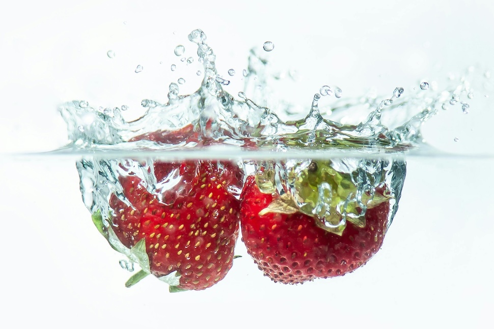 fresh strawberries floating in the water, a refreshing way to stay hydrated during summer.