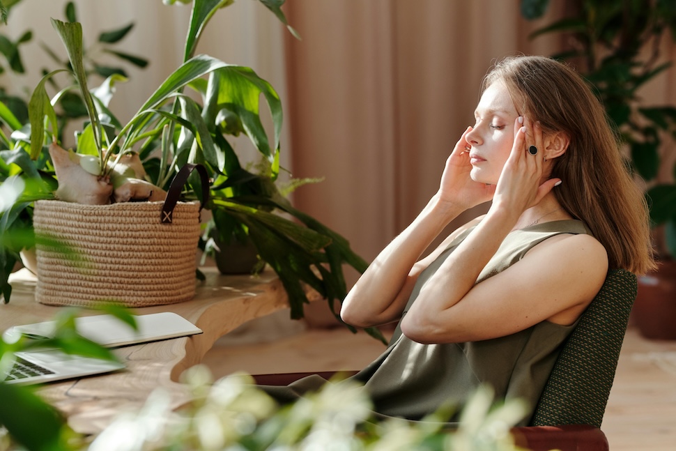 Woman holding her head, suffering from a headache which is a common sign of dehydration.